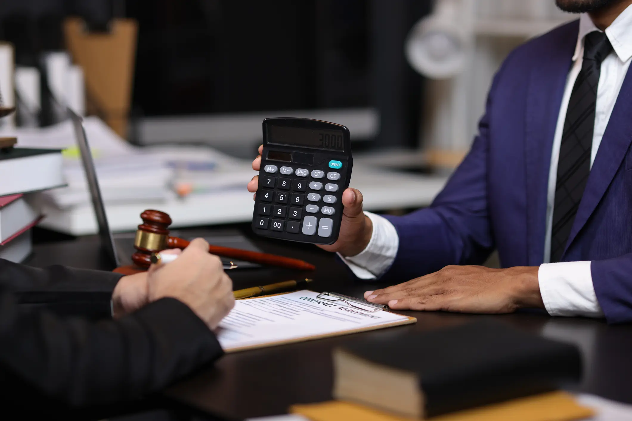 Lawyers discussing legal fees using calculator in law office. Two lawyers are discussing legal fees for a new contract using a calculator, highlighting the financial aspects of legal representation.